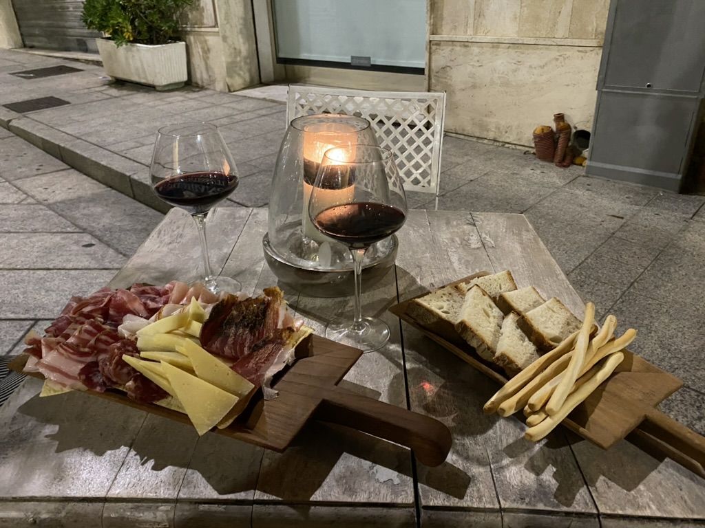 Wine, local cheese, cured meats, and bread served for aperitivo in Olbia old town